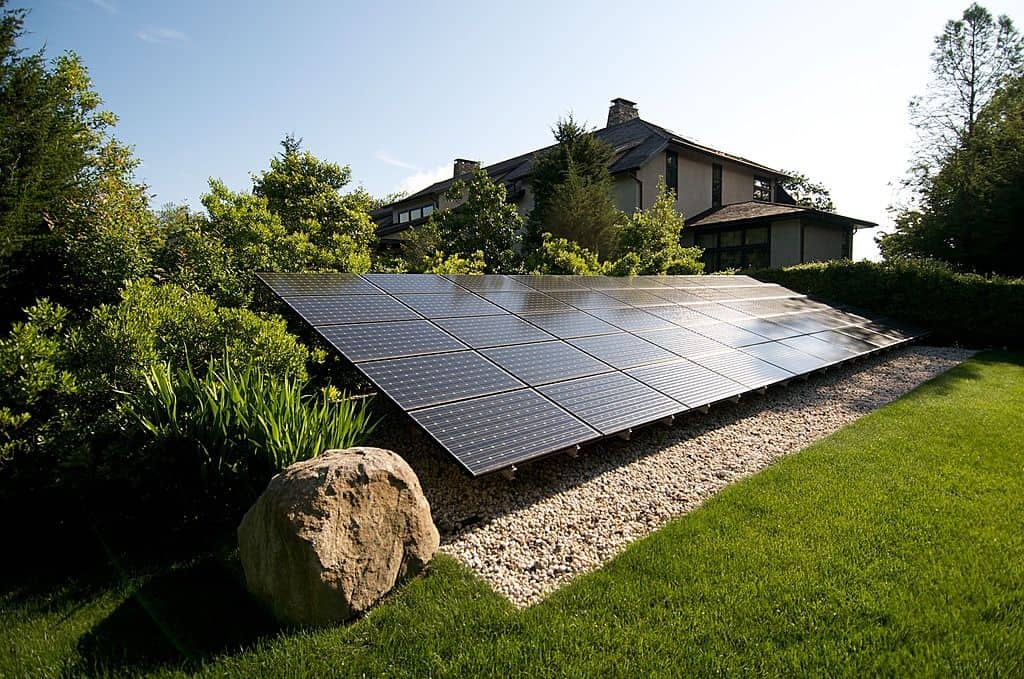Ground-mounted solar panel array positioned behind landscaping, Florida residence