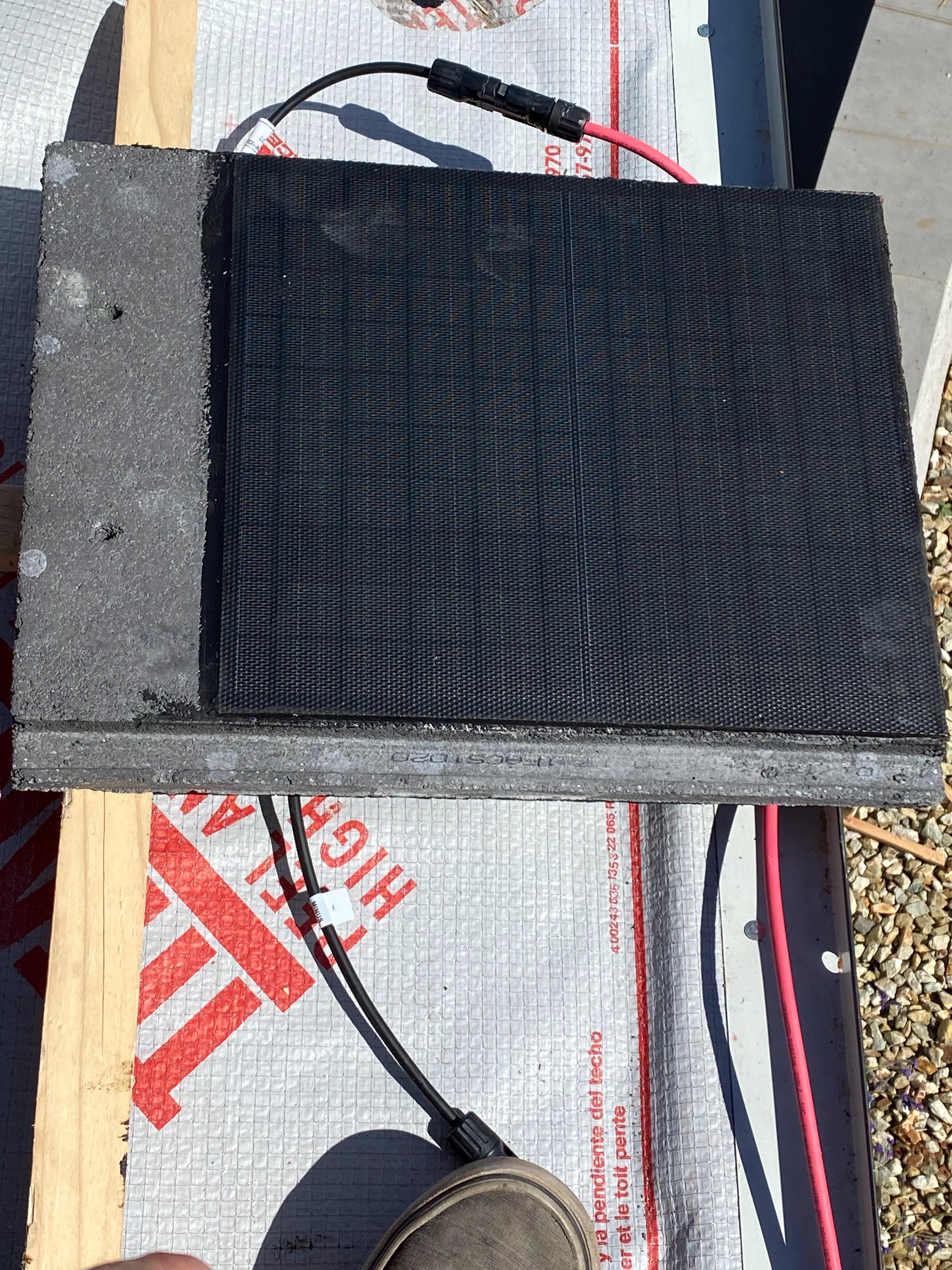 Close up of a solar tile beside a standard concrete tile of the same profile
